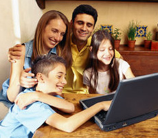 Family gathered around laptop smiling